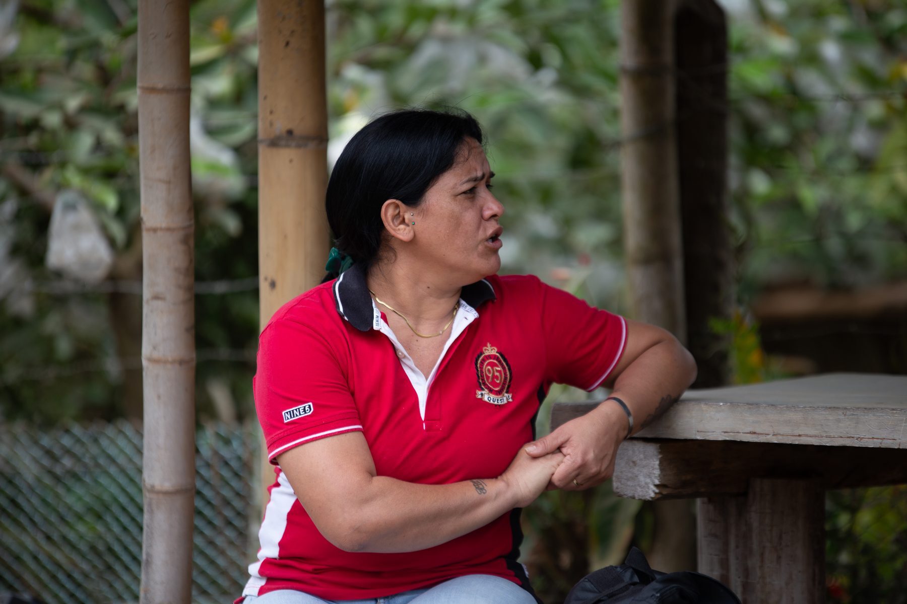 A woman in a red shirt leaning on a rail, laughing