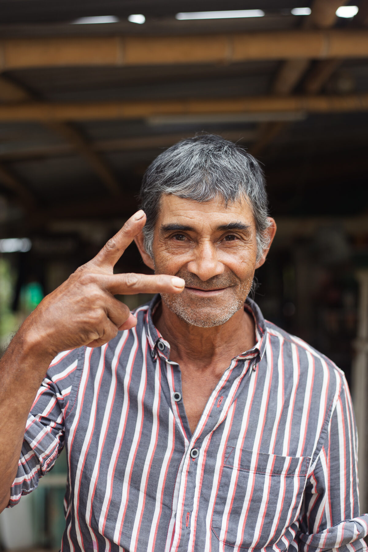 Portrait of Luis, 68, a shopkeeper, smiling at the camera outside his mountain shop